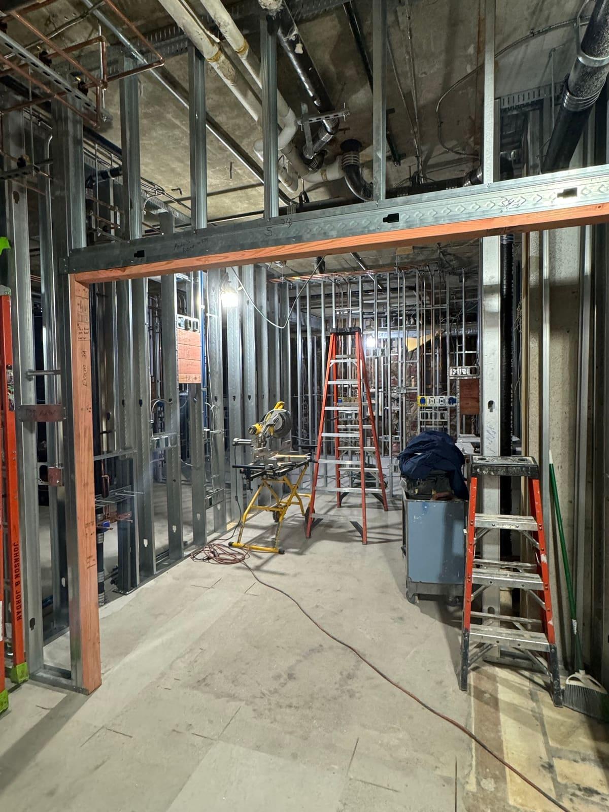 Commercial build-out framed in metal studs, with ladders and a miter saw on site