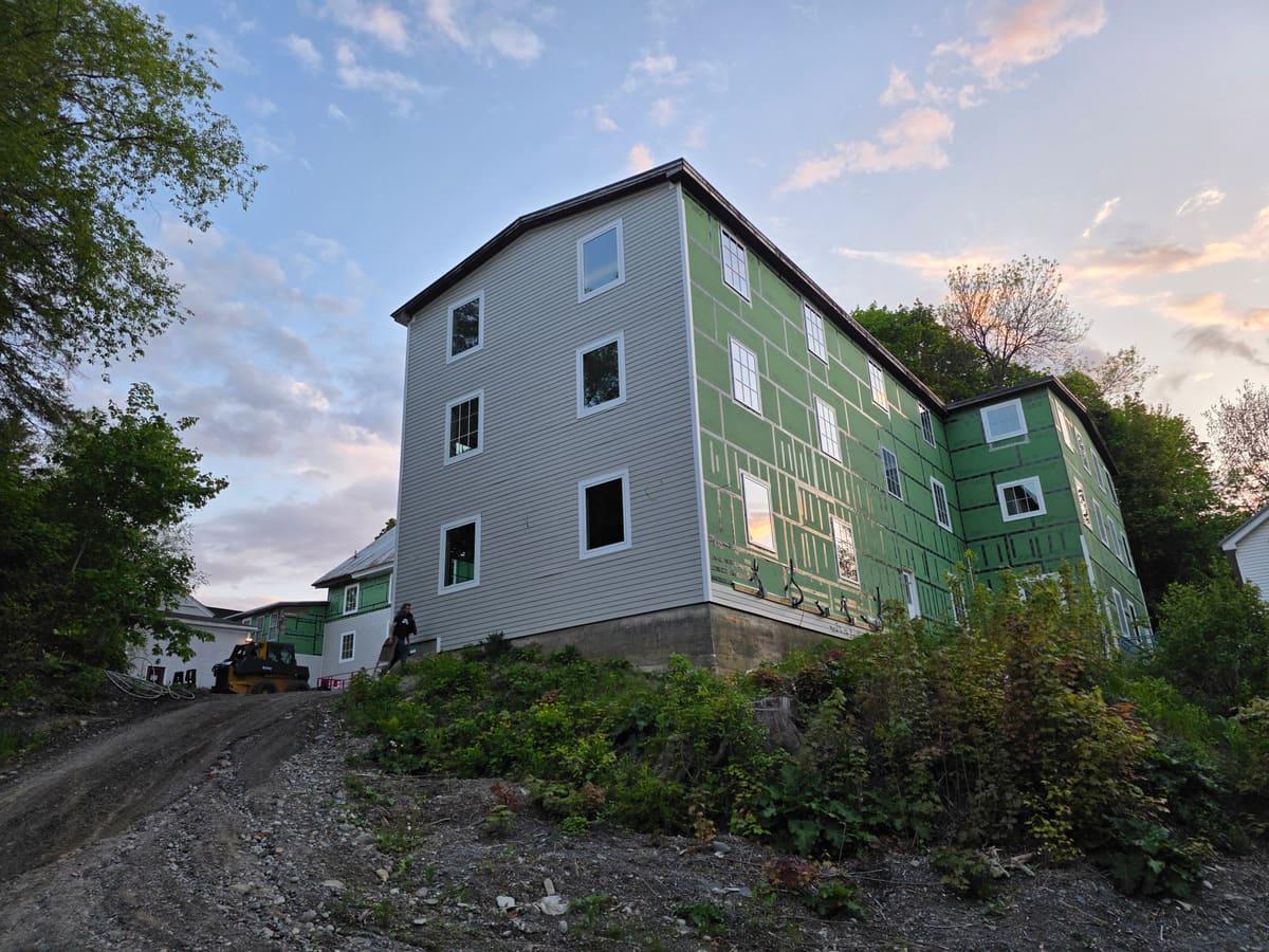 Three-story multi-unit residential building under construction at dusk