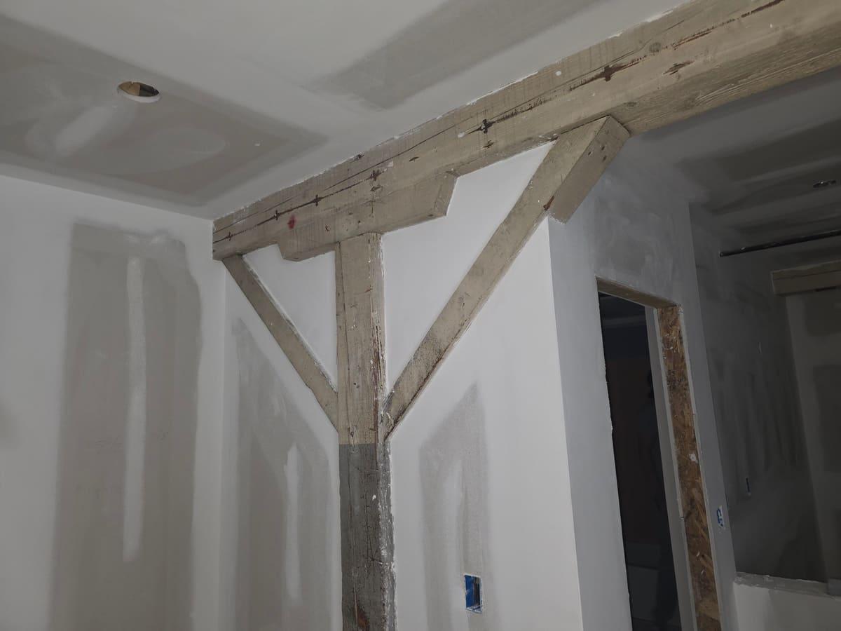 New drywall finished around an exposed timber frame in a renovation