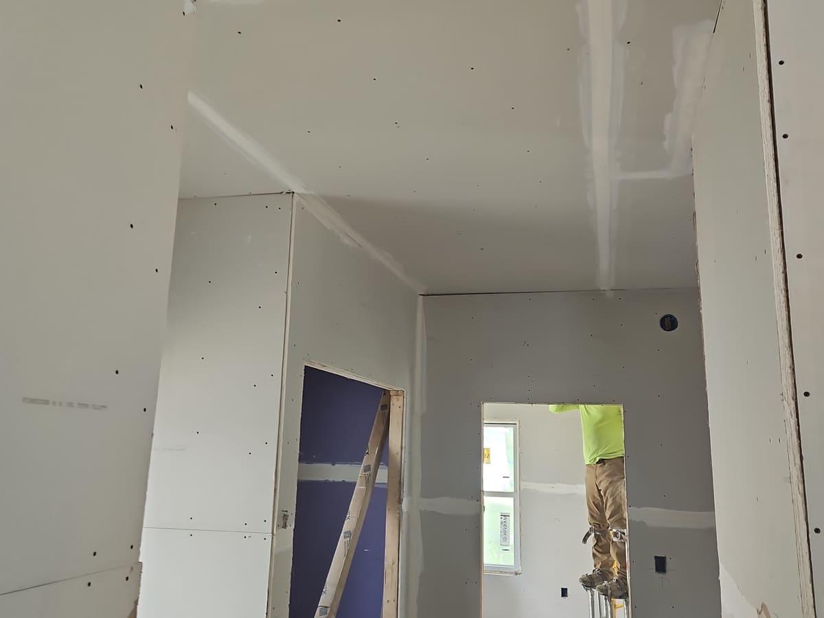 Residential hallway with hung drywall and taped ceiling joints