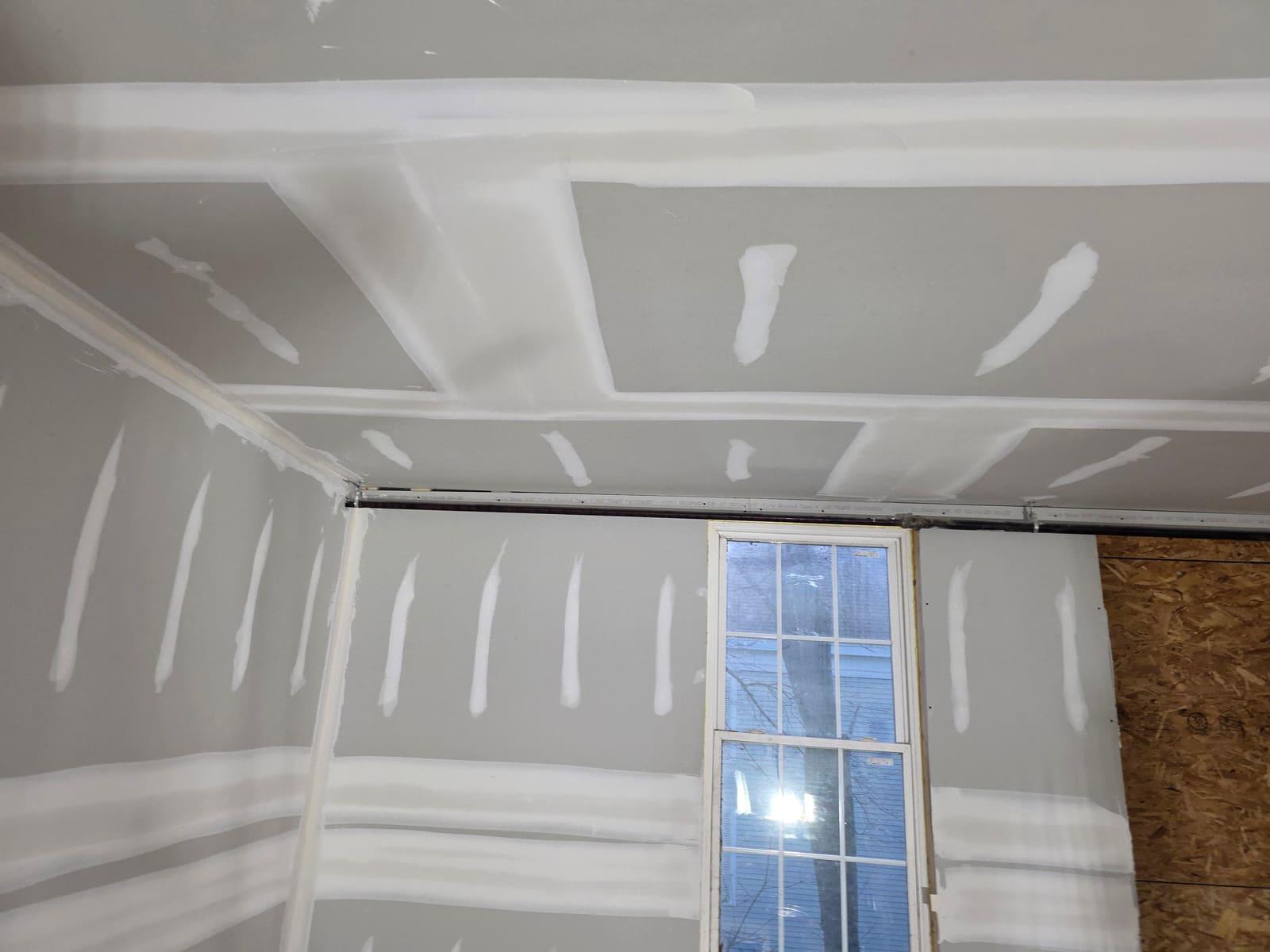 Taped joints and first coat of mud on drywall walls and ceiling