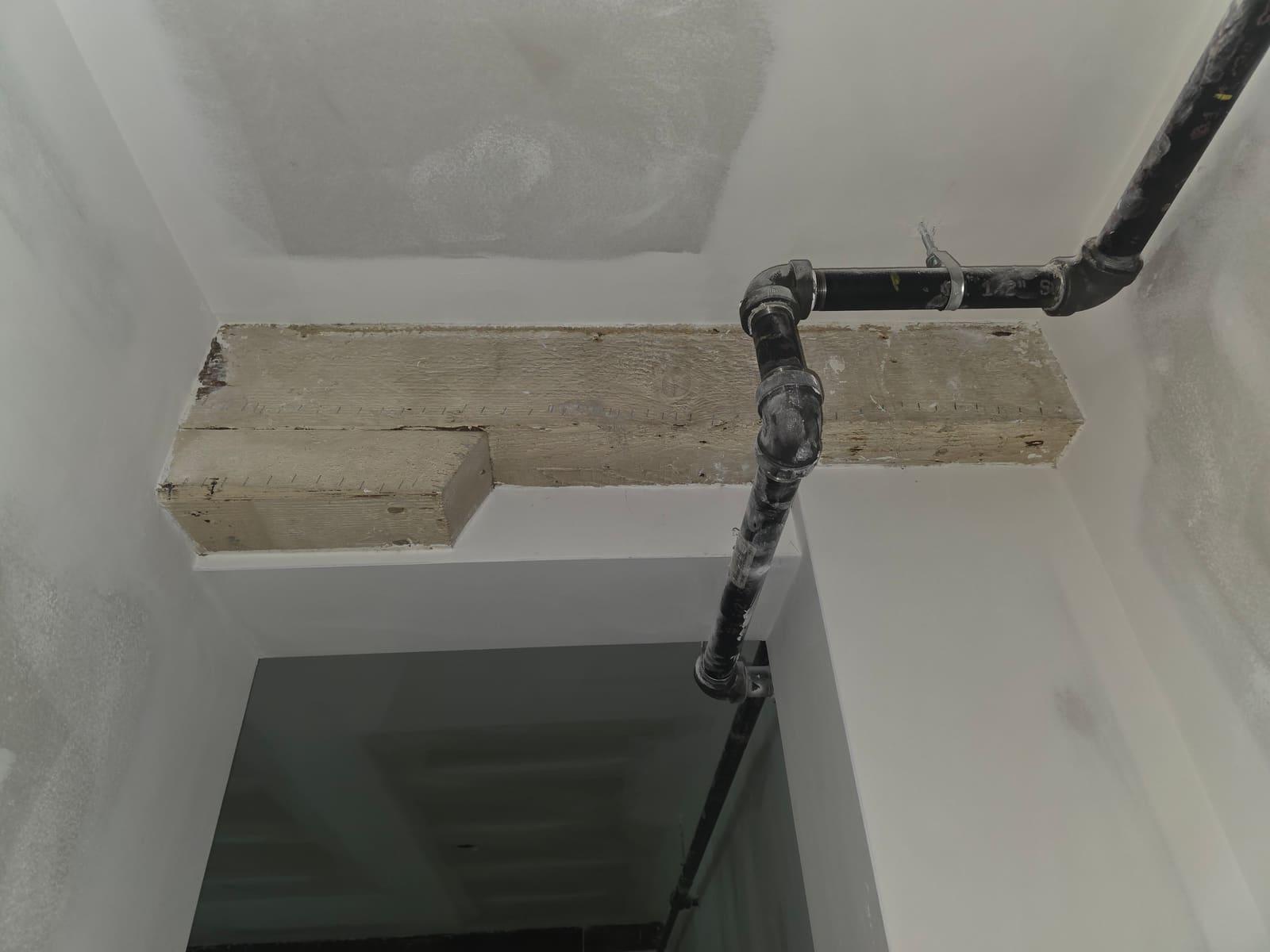 Skim-coated walls and ceiling finished around an exposed timber beam